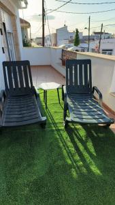 2 Stühle auf einem Balkon mit grünem Gras in der Unterkunft Casa bonita els muntells in Els Muntells