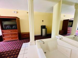 欧塞奇比奇Ozark Inn and Suites的带浴缸的大型浴室和电视。