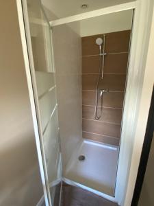 une douche avec une porte vitrée dans une salle de bain dans l'établissement L atelier du golf, à Périgueux