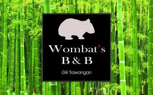 a black sign with a white bear in front of bamboo at Wombat's B&B in Gili Trawangan