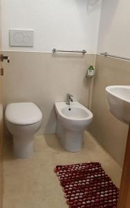 bagno con servizi igienici, lavandino e tappeto rosso di Dody's Home a Otranto Altre 25 foto