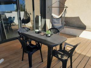 a black table and chairs on a wooden deck at SUPERBE maison, rénovée port de Carro -terrasse,calme & lumière in Martigues