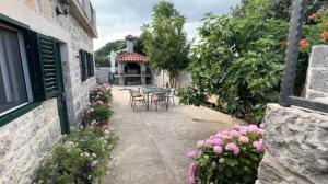 a garden with a table and chairs and flowers at Villa Rosa, Dracevica 46a, Brac in Dračevica