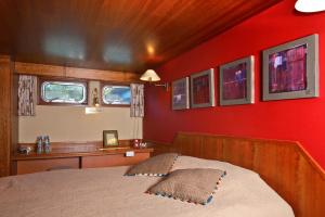 - une chambre avec un lit et un mur rouge dans l'établissement Péniche d'hôtes MS Elisabeth, à Namur