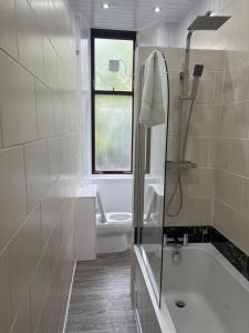 a bathroom with a shower and a tub and a toilet at Glasgow South 2 Bedroom Apartment in Glasgow