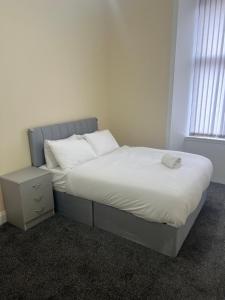 a bedroom with a bed with white sheets and a window at Glasgow South 2 Bedroom Apartment in Glasgow