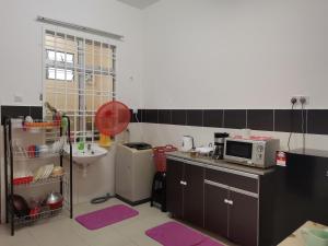 a small kitchen with a sink and a microwave at Dheeya Homestay in Malacca