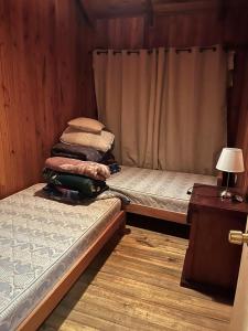 a room with two beds and a table and a lamp at Cabaña en Villa Los Leones in Pinto +3 photos