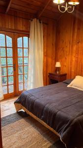 a bedroom with a large bed in a room with wooden walls at Cabaña en Villa Los Leones in Pinto