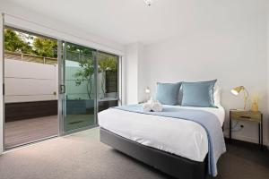 a bedroom with a bed and a sliding glass door at Modern, Spacious Home on Popular Muricata Av - Enjoy Beach, Surf & Sun in Mount Maunganui