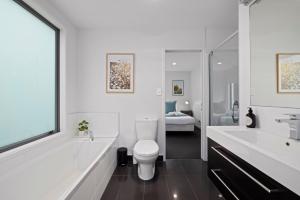 a bathroom with a toilet and a tub and a sink at Modern, Spacious Home on Popular Muricata Av - Enjoy Beach, Surf & Sun in Mount Maunganui +23 photos