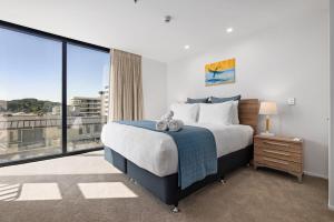 a bedroom with a large bed and a large window at Oceanside Bliss - Absolute Beachfront - Uninterrupted Ocean Views with Pool in Mount Maunganui +29 photos