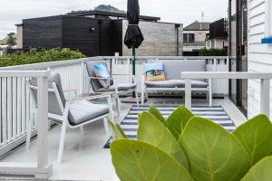 a balcony with two chairs and an umbrella at Awesome Beach House on Oceanview Road in Mount Maunganui