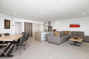 a living room and kitchen with a couch and a table at Oceanside Bliss - Absolute Beachfront - Uninterrupted Ocean Views with Pool in Mount Maunganui