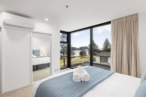 a bedroom with a bed and a large window at Oceanside Bliss - Absolute Beachfront - Uninterrupted Ocean Views with Pool in Mount Maunganui