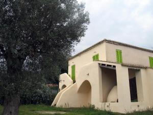 un bâtiment blanc avec des volets verts et un arbre dans l'établissement Il Canto di Kokopelli Country Houses, à Brattirò