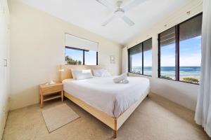 Un dormitorio con una cama grande y grandes ventanales. en Mintee 1 by Discover Stradbroke, en Point Lookout