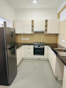 Una cocina con gabinetes blancos y un refrigerador negro. en Luxe 3BR Haven at Iconic Galaxy, en Sri Jayewardenepura Kotte