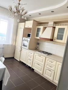a kitchen with white cabinets and a chandelier at Двухкомнатная квартира в ЖК Жана Алем in Atyraū