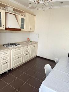 a kitchen with white cabinets and a table with chairs at Двухкомнатная квартира в ЖК Жана Алем in Atyraū +2 photos