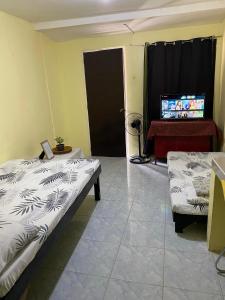 ein Zimmer mit zwei Betten und einem Laptop auf einem Tisch in der Unterkunft Perlies Inn Studio House in Tanay