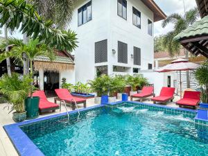 une piscine en face d'une maison avec des chaises rouges et d'un bâtiment dans l'établissement Amara Beach Resort Koh Phangan, à Haad Yao
