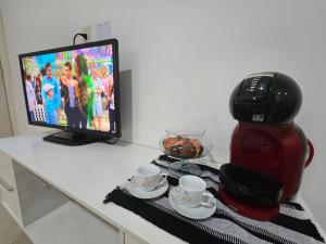 a table with a coffee pot and cups and a television at Marques Beach House MCZ in Maceió