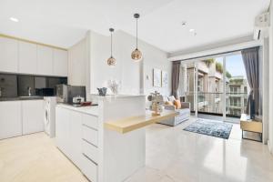 a kitchen and living room with white cabinets at Dahayu by Kozystay - Paskal in Bandung