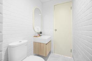ein weißes Badezimmer mit Waschbecken und Spiegel in der Unterkunft Mukava by Kozystay - Grogol in Jakarta