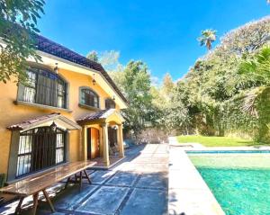 a house with a bench next to a swimming pool at CasonaPalmira alberca climatizada en zona exclusiva in Cuernavaca