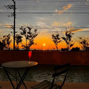 a table and chair with a glass of wine at sunset at KAMOME SLOW HOTEL the COMPACT in Awaji
