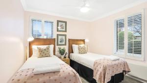 een slaapkamer met twee bedden en twee ramen bij Coachwood Cottage in Robertson