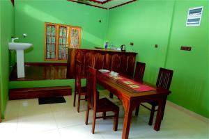 een eetkamer met een houten tafel en groene muren bij Columbus villa in Jaffna