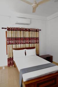 een slaapkamer met een groot bed en een gordijn bij Columbus villa in Jaffna