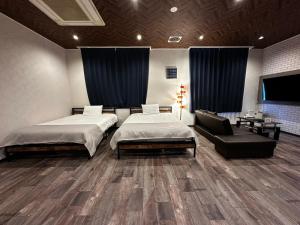 une chambre avec deux lits et une chaise et une télévision dans l'établissement Economy Hotel Upashi, à Asahikawa