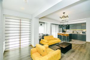 a living room with two yellow chairs and a kitchen at Park Azure Deluxe Home 526 in Baku