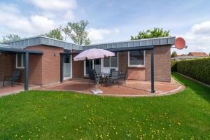 ベンサージールにあるFerienhaus Friesenkroneのパティオ(テーブル、傘付)が備わる家