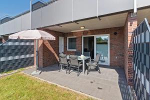 a patio with a table and chairs and an umbrella at Ferienhaus Domingo in Bensersiel