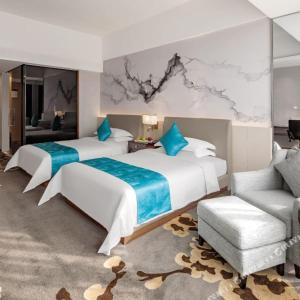 a hotel room with two beds and a chair at Huaqiang Plaza Hotel Shenzhen, Enjoy Complimentary Mini Bar & Night Snack, Add breakfast - enjoy complimentary afternoon tea in Shenzhen