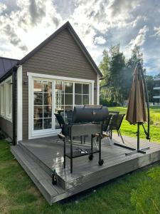 a deck with a grill and an umbrella at Melluži tiny house 60m2 in Jūrmala