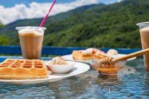 a table with two plates of waffles and two drinks at Rusikos guest house in Oni