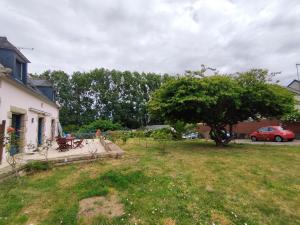 a yard with a tree and a house at Au Pti' Bonheur in Saint-Coulomb