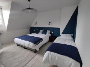 a bedroom with two beds with blue and white sheets at Au Pti' Bonheur in Saint-Coulomb