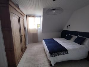 a bedroom with a bed with a blue blanket on it at Au Pti' Bonheur in Saint-Coulomb