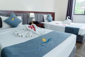 a hotel room with two beds with swans on them at Bạch Đằng Hạ Long Hotel in Ha Long