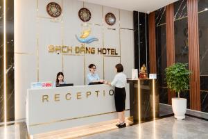 two people standing at a reception desk in a hotel at Bạch Đằng Hạ Long Hotel in Ha Long