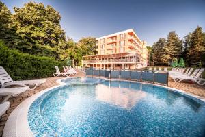 a swimming pool with chairs and a building in the background at Gloria Hotel - All Inclusive in Saints Constantine and Helena