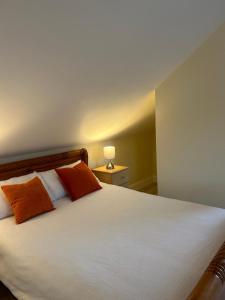 a bedroom with a white bed with two orange pillows at Mountain View in Dawros