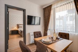 een eetkamer met een tafel en stoelen en een raam bij Prestige Central Apartments in Varna