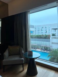 a room with a chair and a table and a large window at Pride Plaza Hotel, Aerocity New Delhi in New Delhi